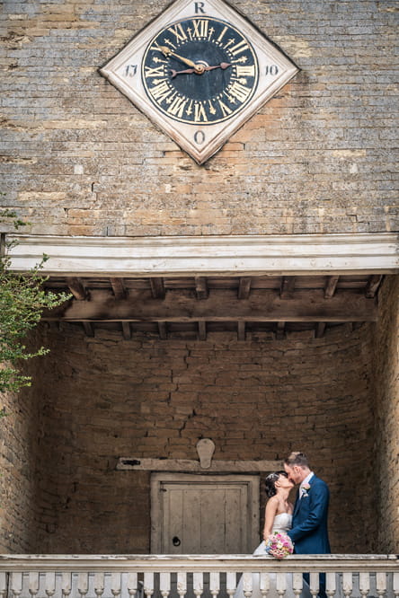 Bride and groom kiss on balcony