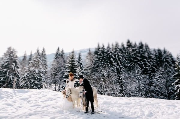 Bride and groom in snow with horses