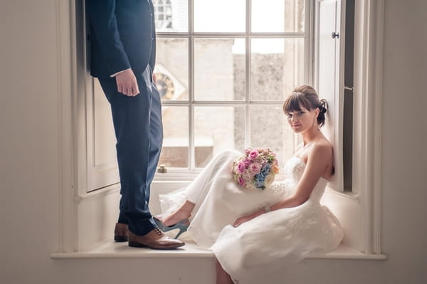 Bride sitting on window ledge