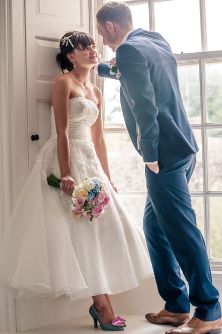 Bride and groom standing on window ledge