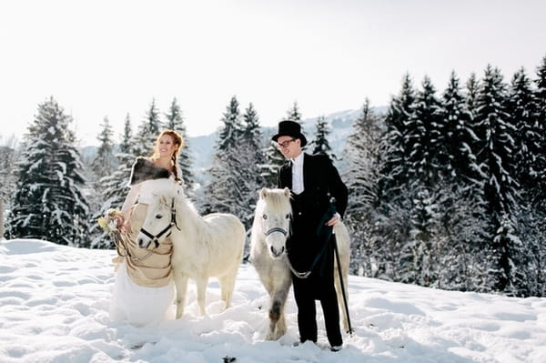 Bride and groom in snow with horses