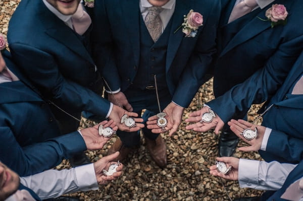 Groomsmen holding pocket watches