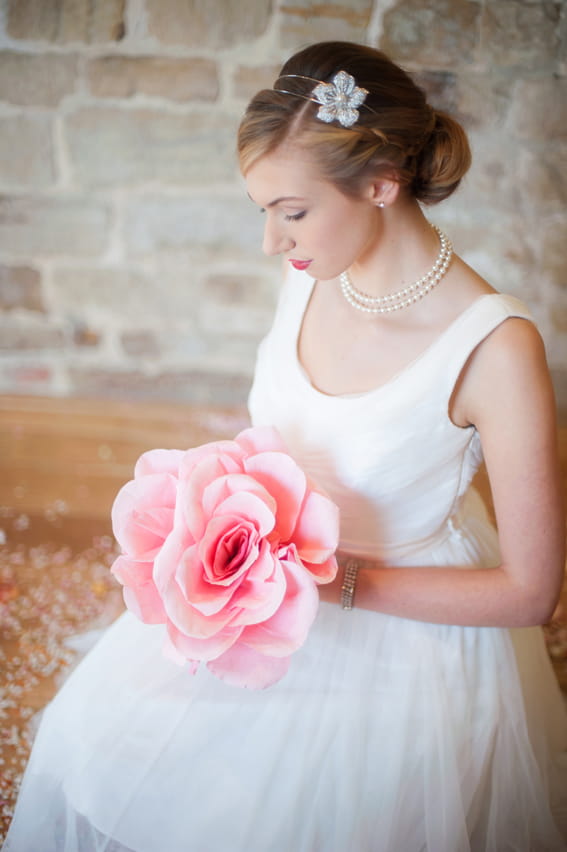 Bride sitting holding large pink flower