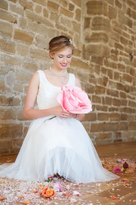 Bride sitting holding large pink flower