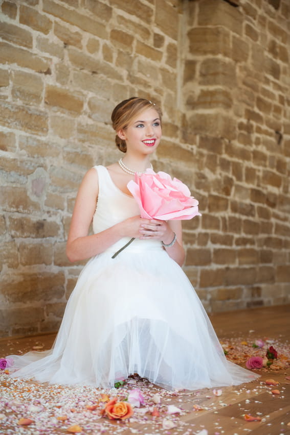 Bride sitting holding large pink flower