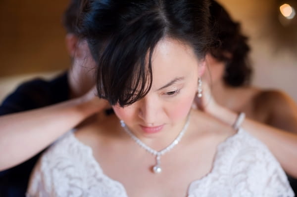 Bride putting necklace on