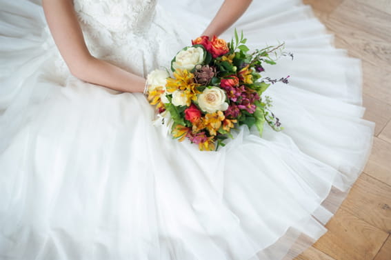 Bride sitting holding colourful wedding bouquet