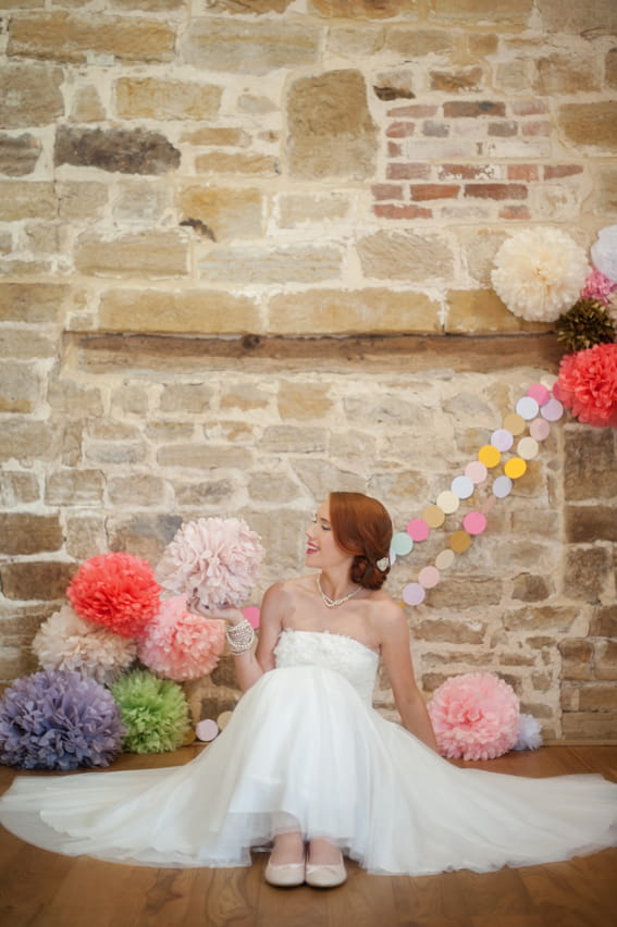 Bride sitting on floor looking at paper pom pom