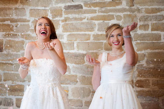 Two brides throwing confetti