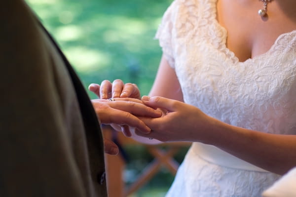 Bride putting ring on groom's finger