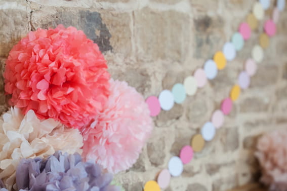 Coloured paper pom poms hanging from wall