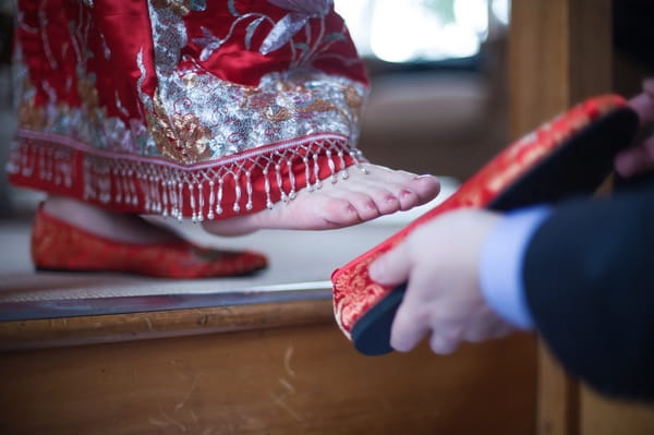 Groom putting shoe on bride's foot