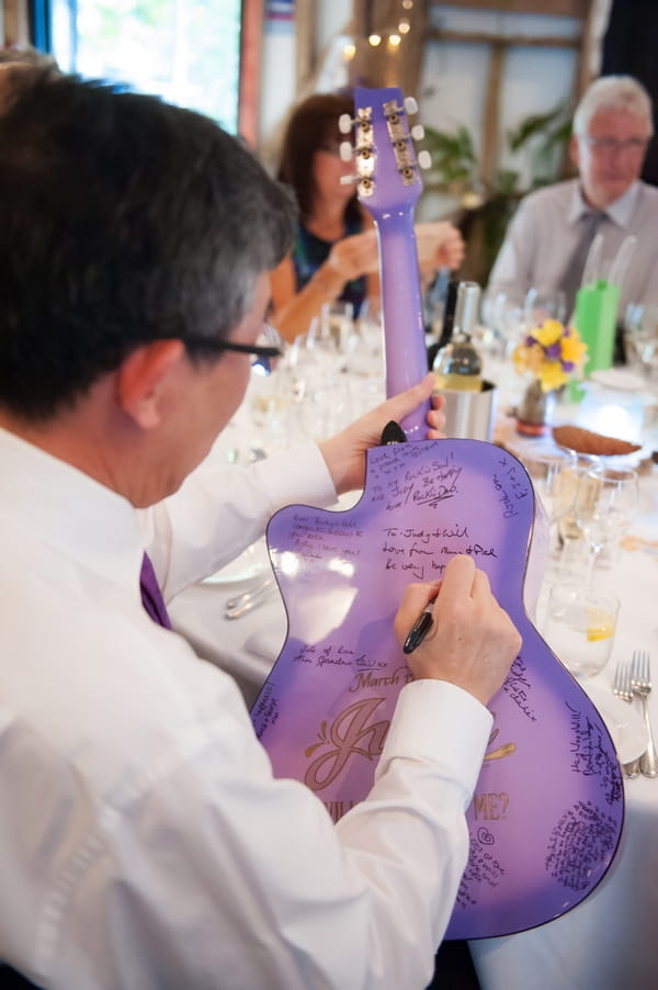 Man writing wedding message on guitar