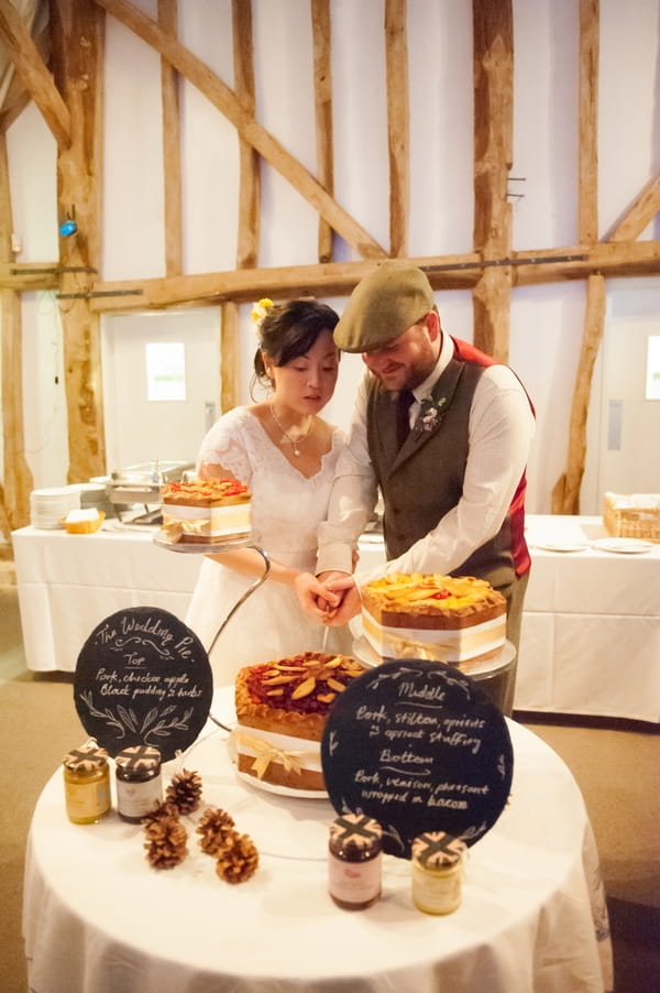 Bride and groom cutting pork pie wedding cake