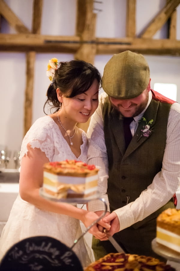 Bride and groom cutting pork pie wedding cake