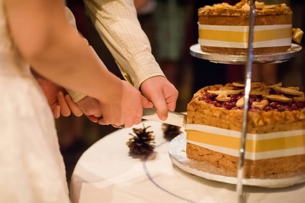 Bride and groom cutting pork pie wedding cake