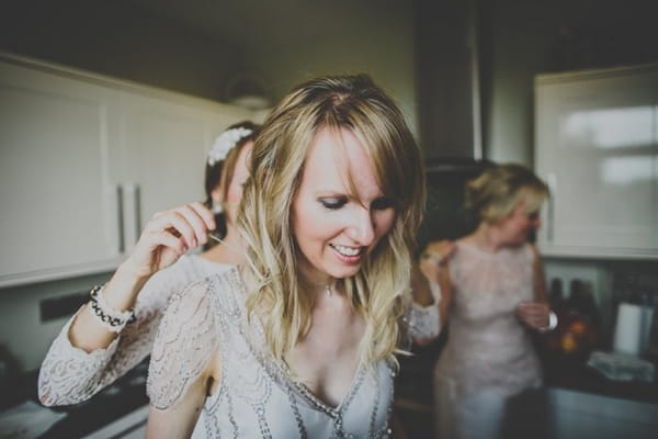 Bride getting help putting necklace on