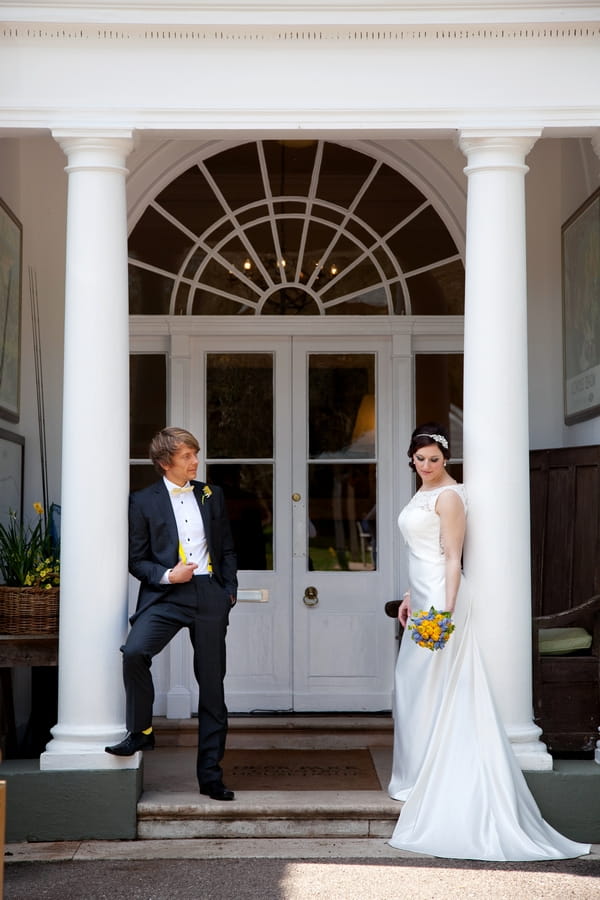 Bride and groom leaning on pillars of Deer Park Hotel