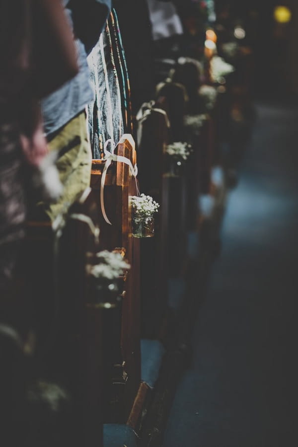 Jars of flowers at end of church pews