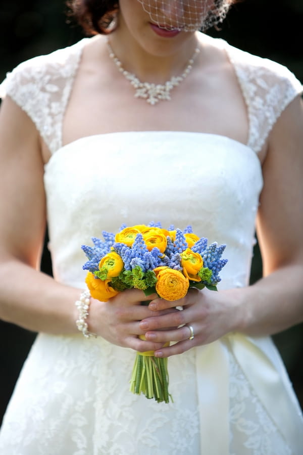 Bride holding yellow and blue bouquet