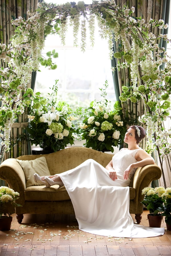 Bride laying on sofa surrounded by spring flowers