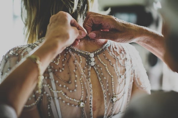 Bride getting help putting necklace on