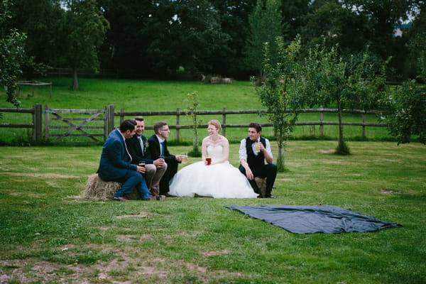 Bride and groomsmen sitting on hay bale