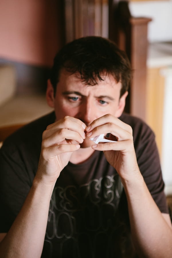 Groom making origami paper crane