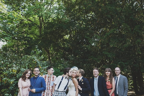 men kissing bride on cheeks