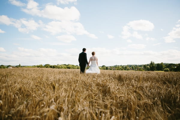 Bride and groom walking in corn field