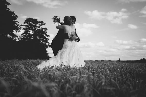 Bride and groom hugging in corn field