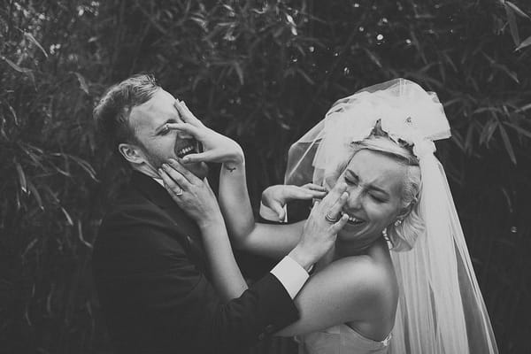 Bride and groom with hands over faces