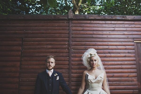 Bride and groom in front of fence