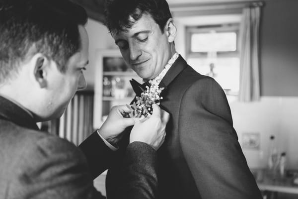 Best man helping groom with buttonhole