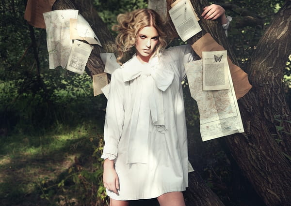Model standing under tree with book pages stuck to it