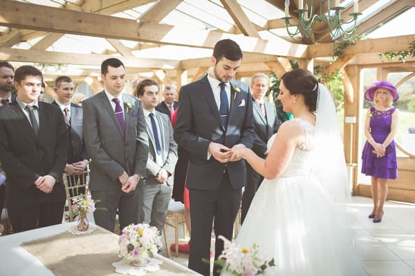 Groom putting ring on bride's finger