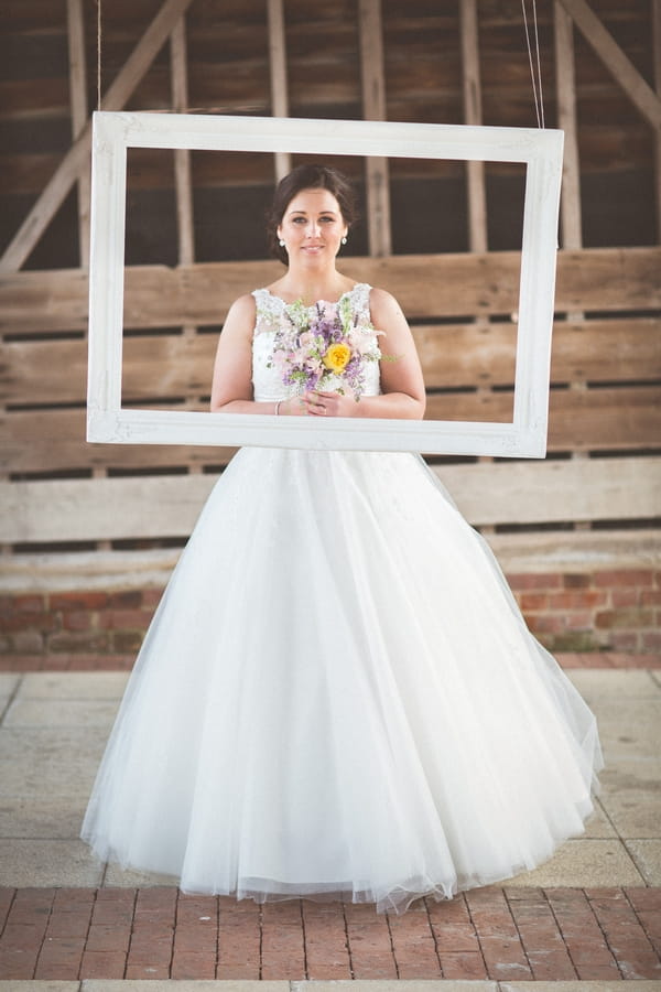 Bride standing behind picture frame