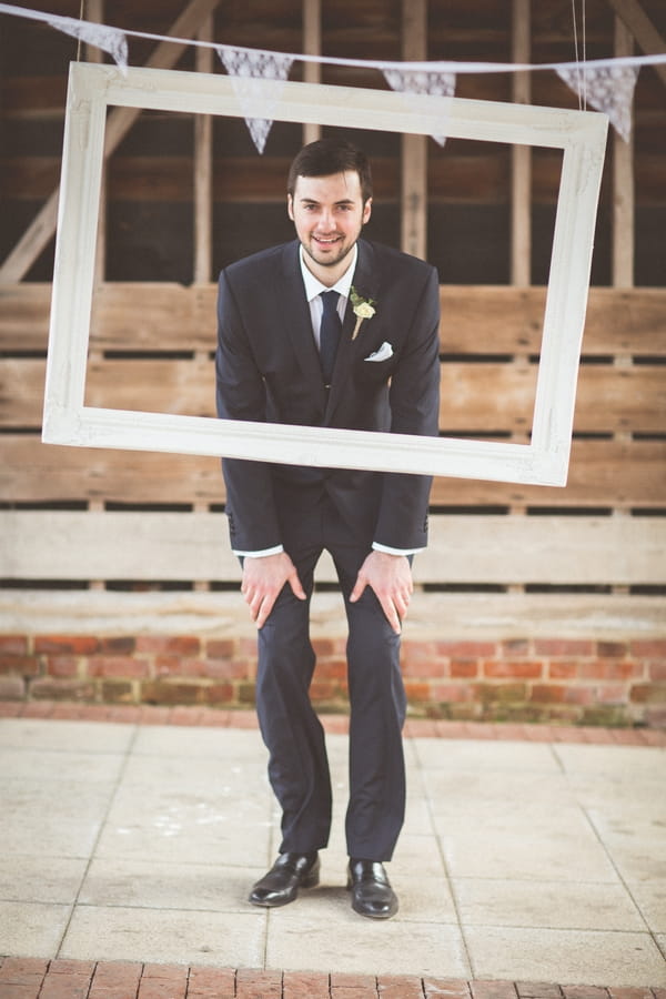 Groom standing behind picture frame