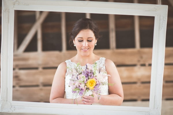 Bride standing behind picture frame