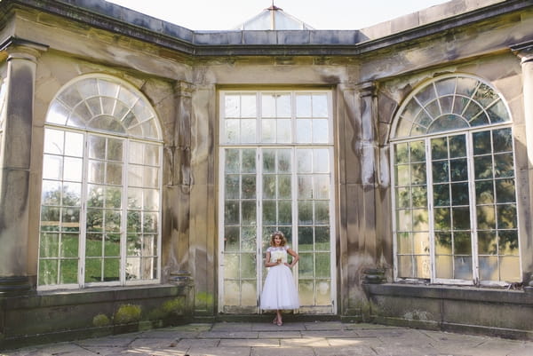 1950s bride standing in front of large glass doors