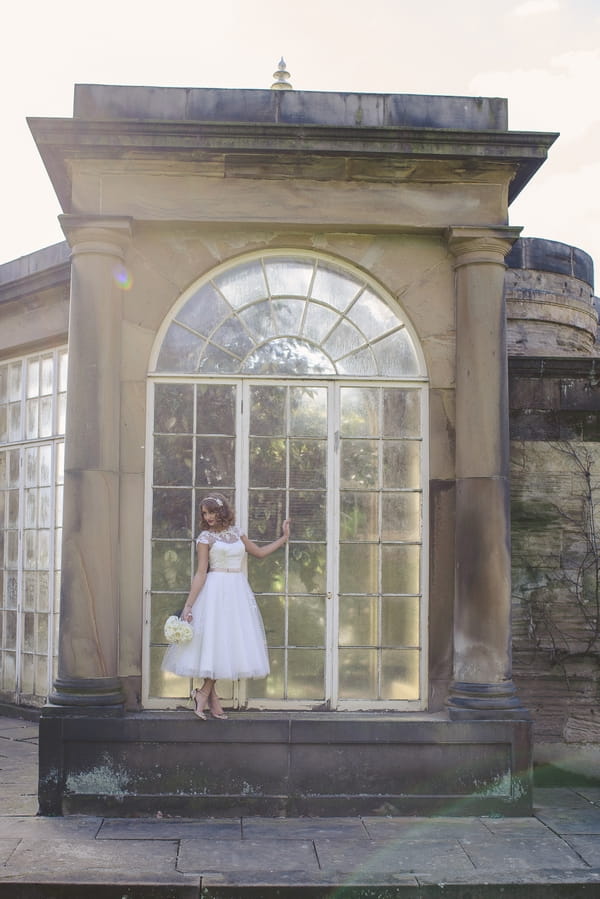 1950s bride standing in front of large glass window