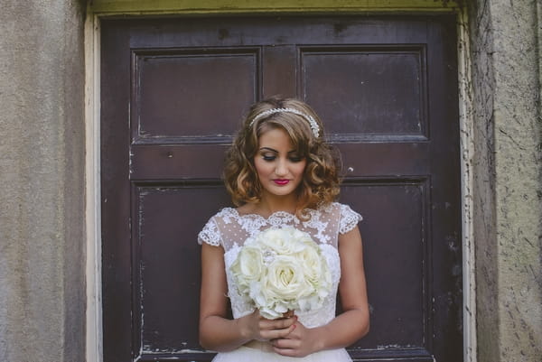 1950s bride looking down at bouquet