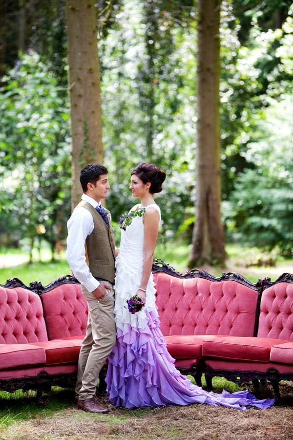 Bride and groom in front of couch in woodland