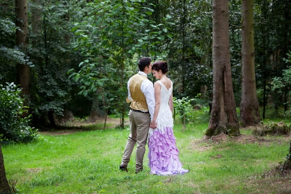 Bride and groom holding hands in woods