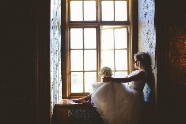 1950s bride sitting on window ledge