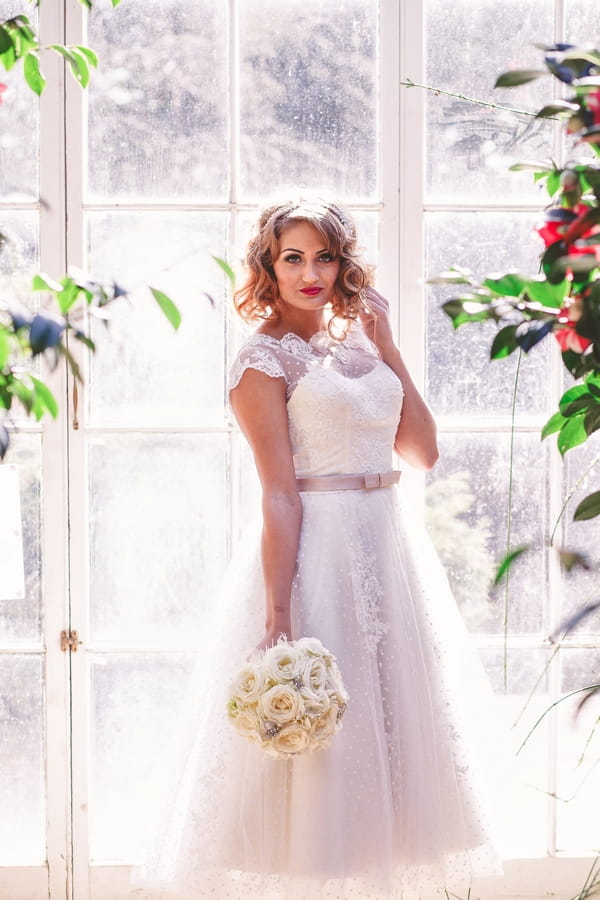 1950s bride standing by large window