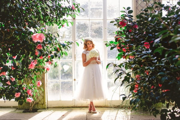 1950s bride standing in between trees indoors