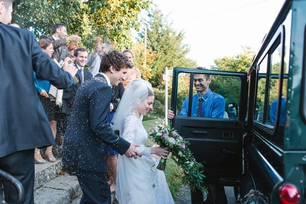 Bride and groom getting in wedding car