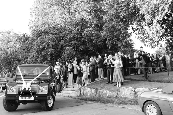 Bride and groom leaving in land rover wedding car