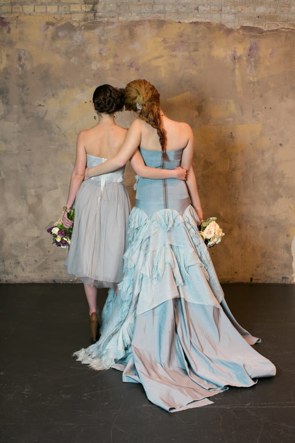 Bride and bridesmaid with arms around each other